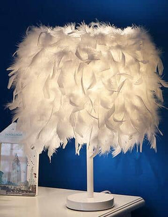 Elegant sänglampa med vita fjädrar